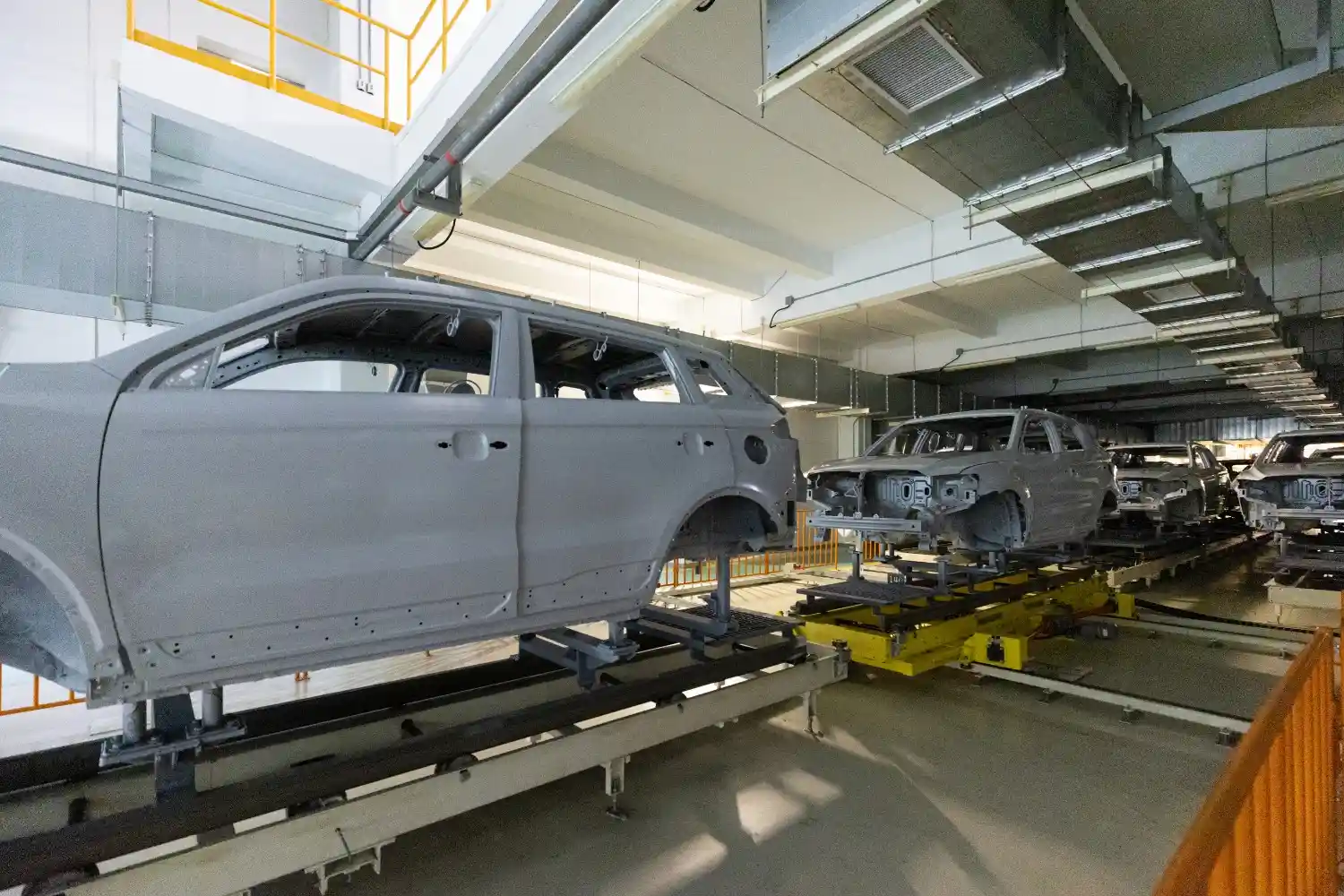 Insights Blog 9 Automotive factory assembly line with unfinished car bodies moving through a vehicle manufacturing facility.