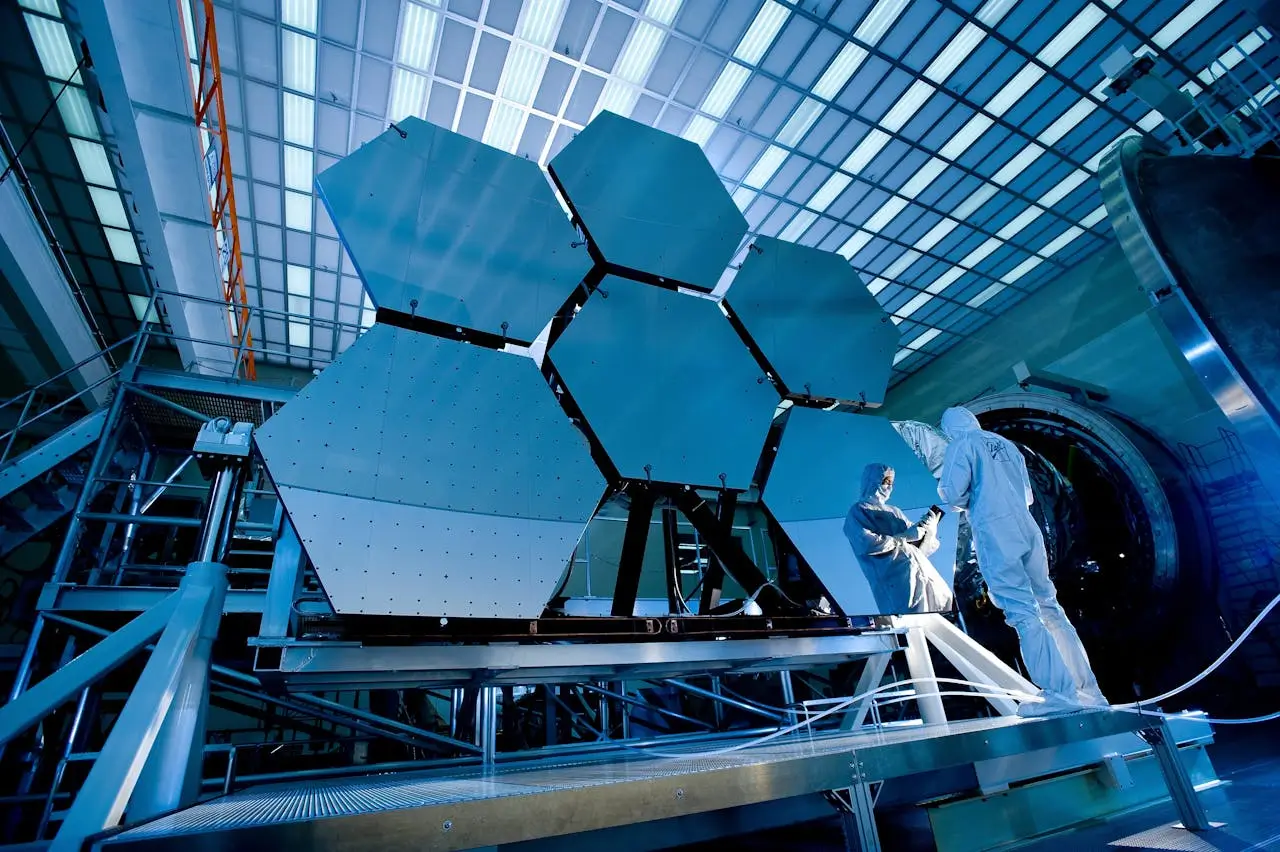 Insights Blog 8 Engineers in protective suits working in a high-tech cleanroom with precision equipment, illustrating controlled environments sensitive to airborne contamination.