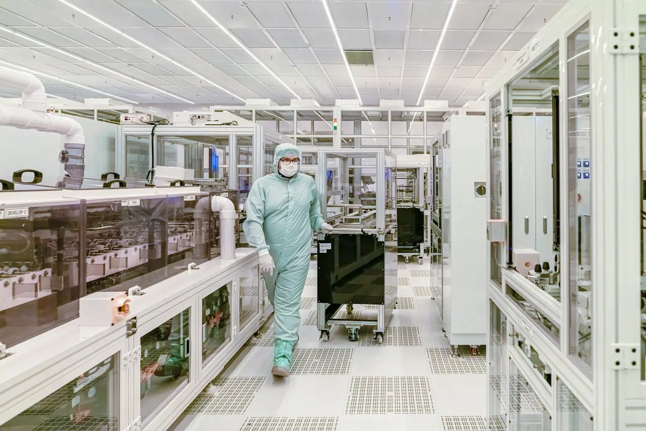 Insights Blog 3 Cleanroom technician in full protective suit moving equipment through a controlled manufacturing environment with enclosed systems and airflow controls.
