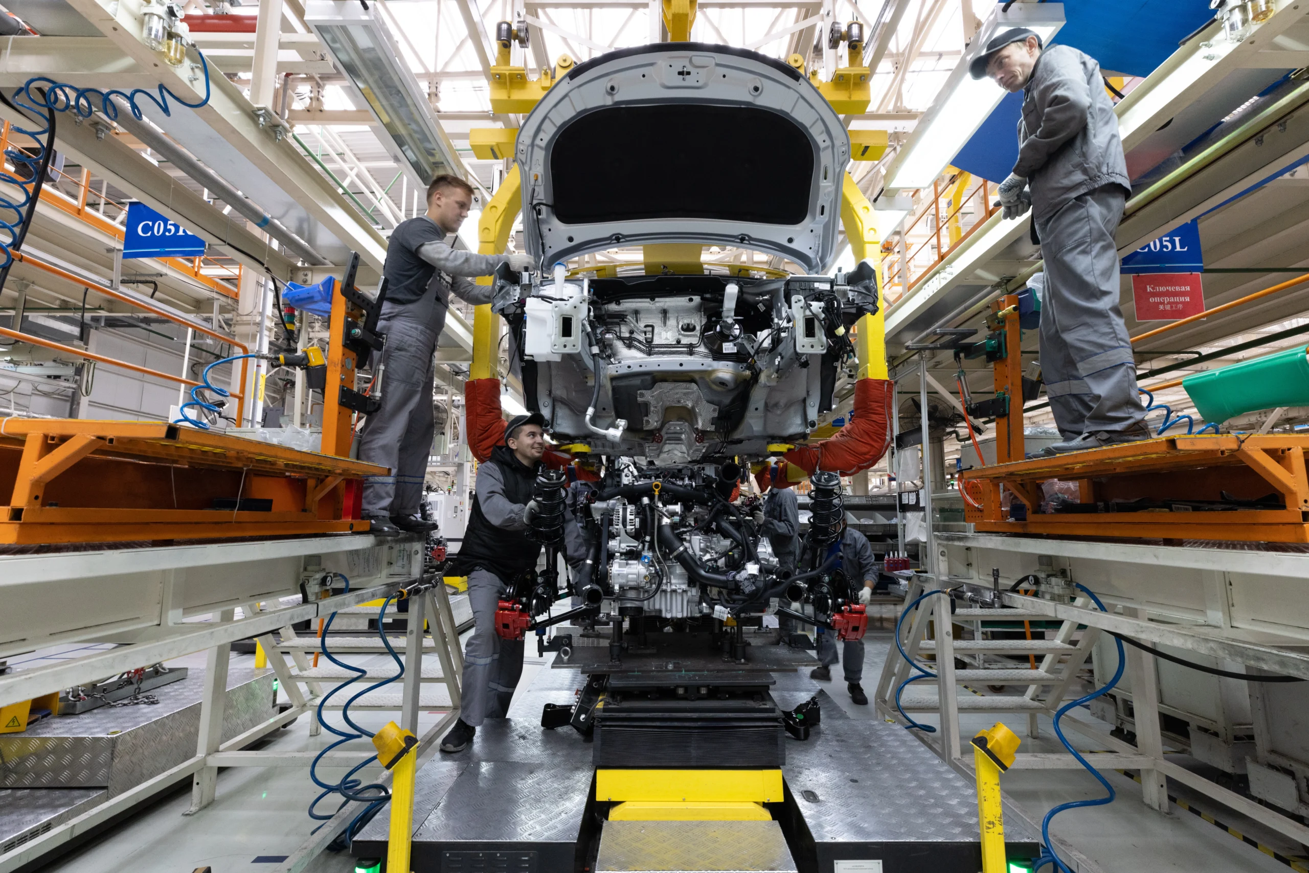 Insights Blog 5 Automotive factory workers assembling a vehicle on a production line inside a car manufacturing plant.