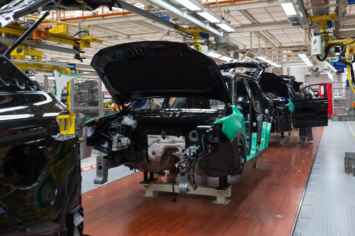 Insights Blog 8 Car bodies moving along an automotive factory assembly line during vehicle production and inspection.