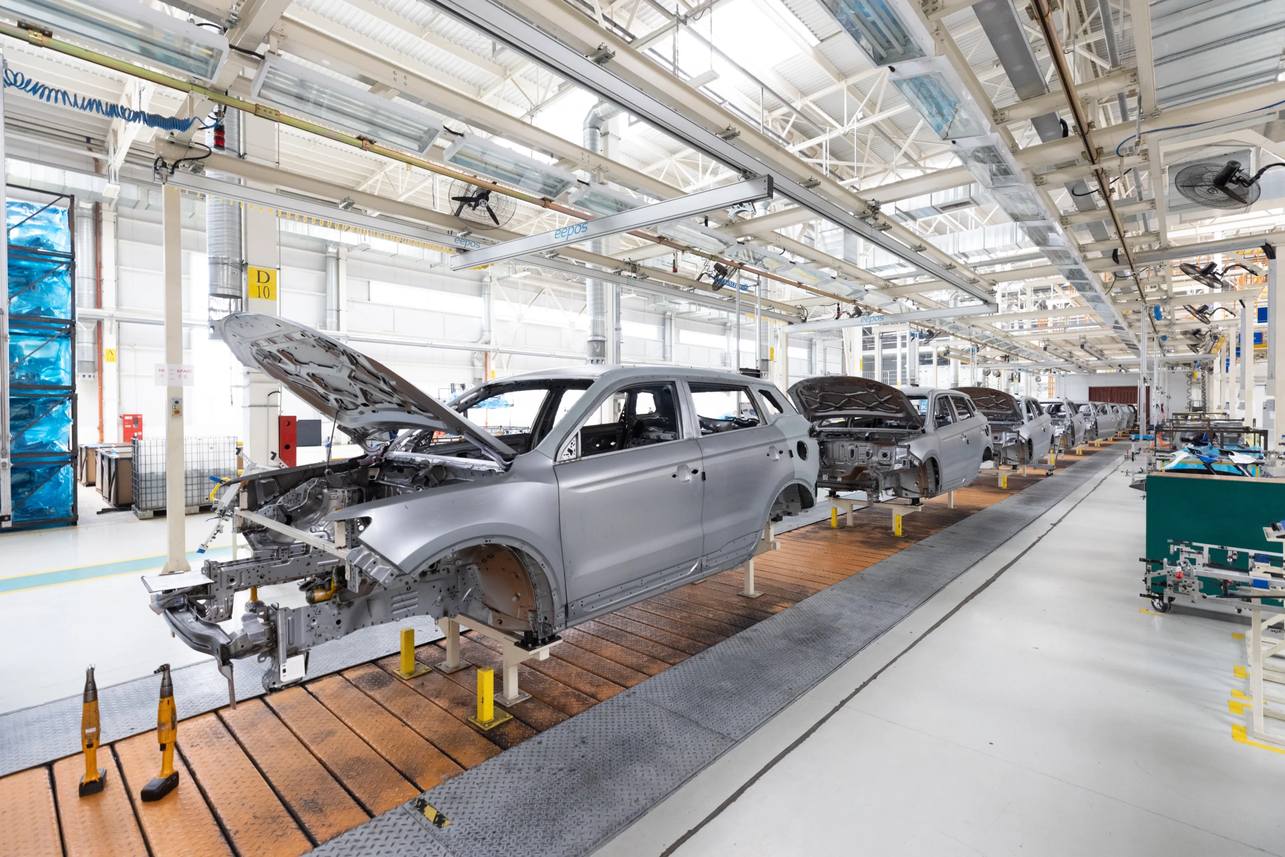 Insights Blog 3 Automotive manufacturing assembly line with car bodies moving through a factory production line during vehicle assembly.