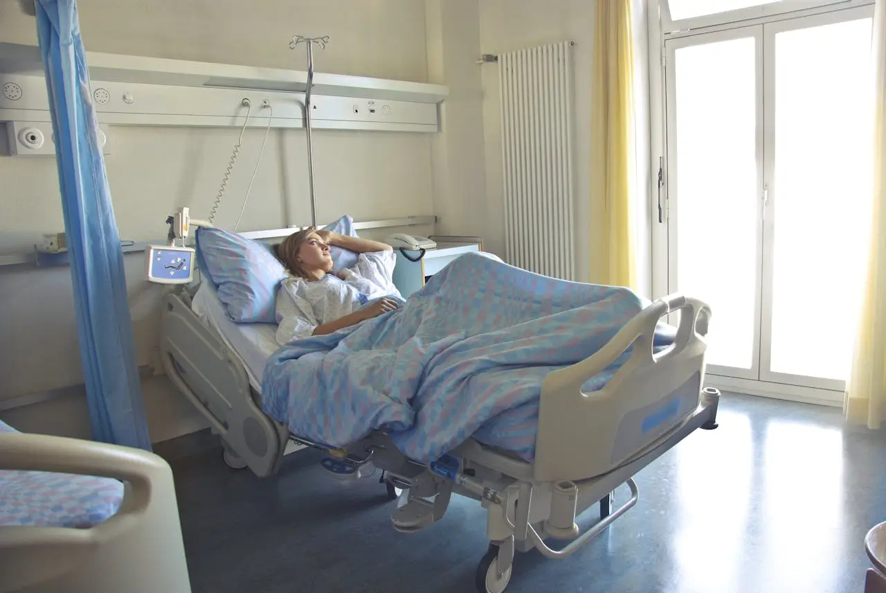 Insights Blog 5 Patient resting in a hospital bed inside a clinical care room with medical equipment and natural light.