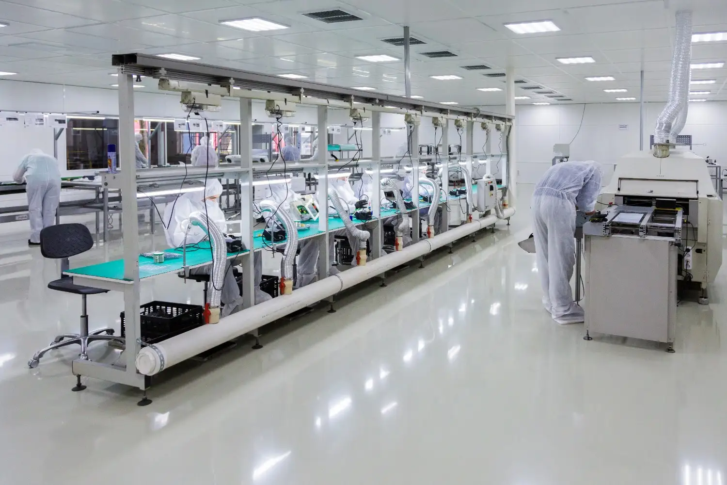 Insights Blog 8 Pharmaceutical manufacturing cleanroom with workers in protective suits operating equipment in a controlled, sterile environment.