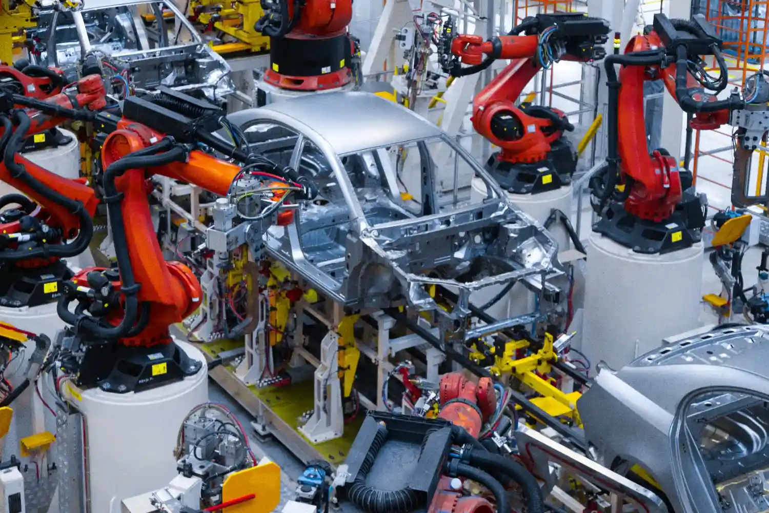 Insights Blog 1 Automated automotive assembly line with robotic arms assembling a car body, illustrating controlled manufacturing environments in vehicle production.