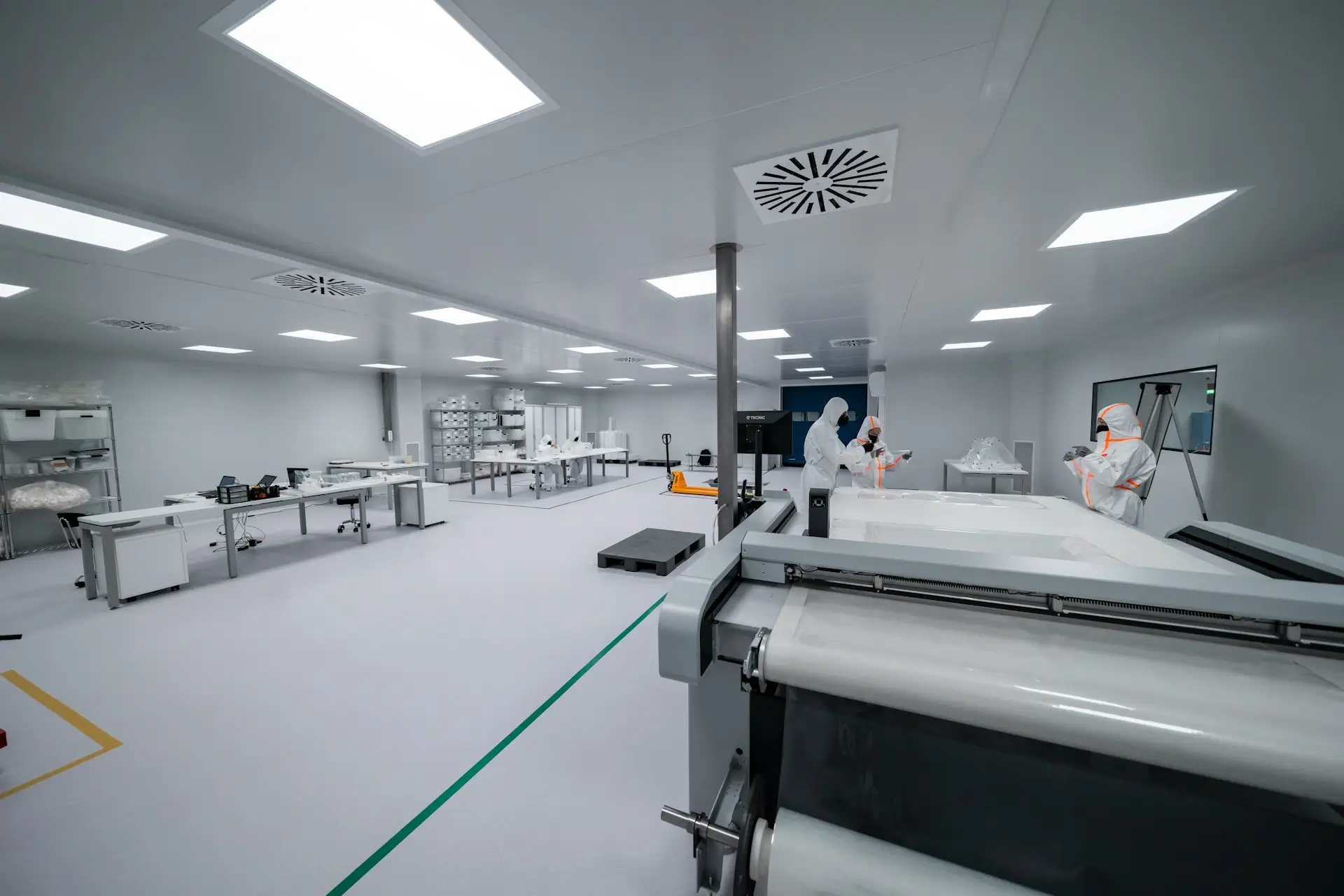 Insights Blog 7 Cleanroom manufacturing facility with technicians in full protective suits operating precision equipment.