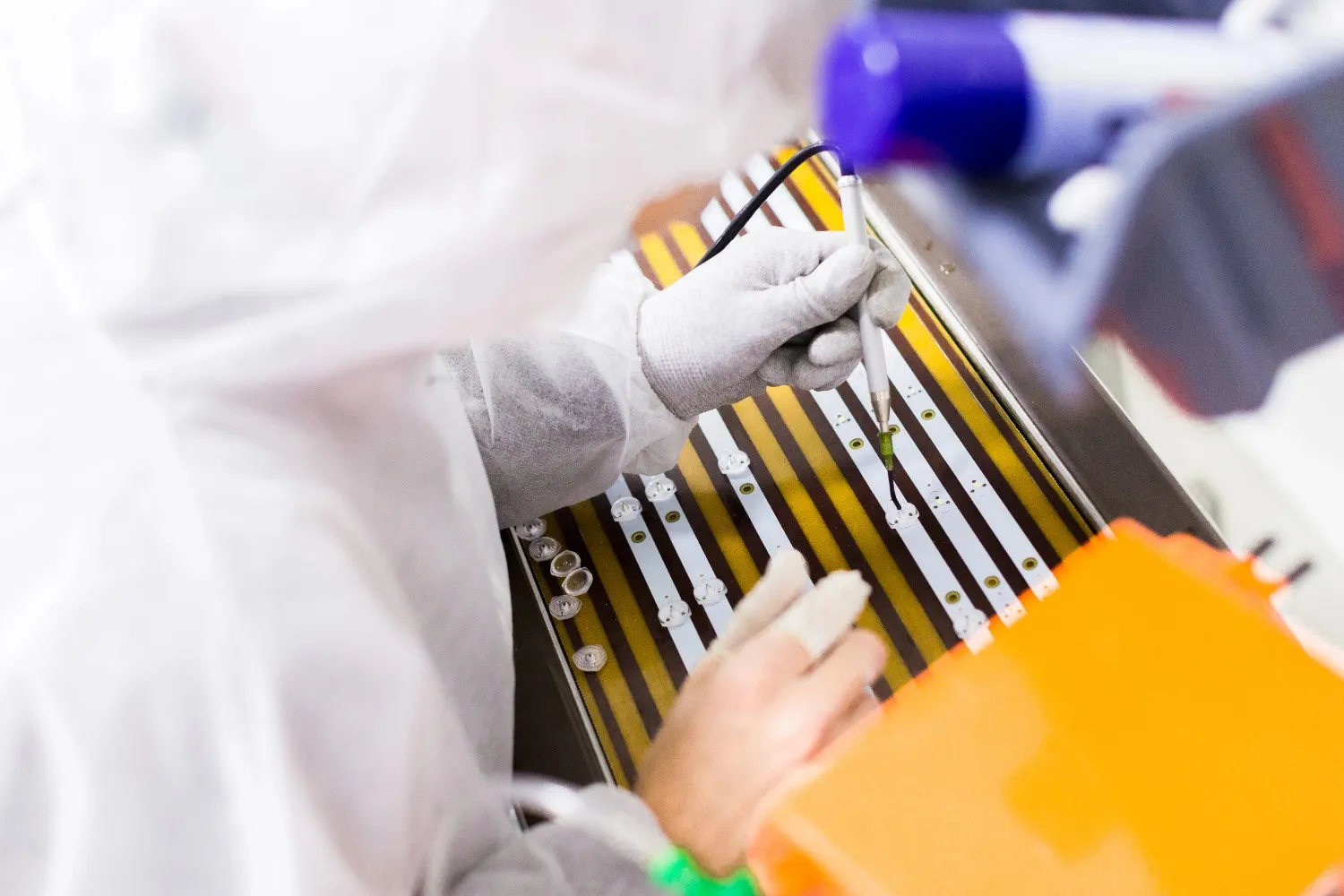 Cleanroom worker handling electronic components during a precision manufacturing process in a controlled production environment.