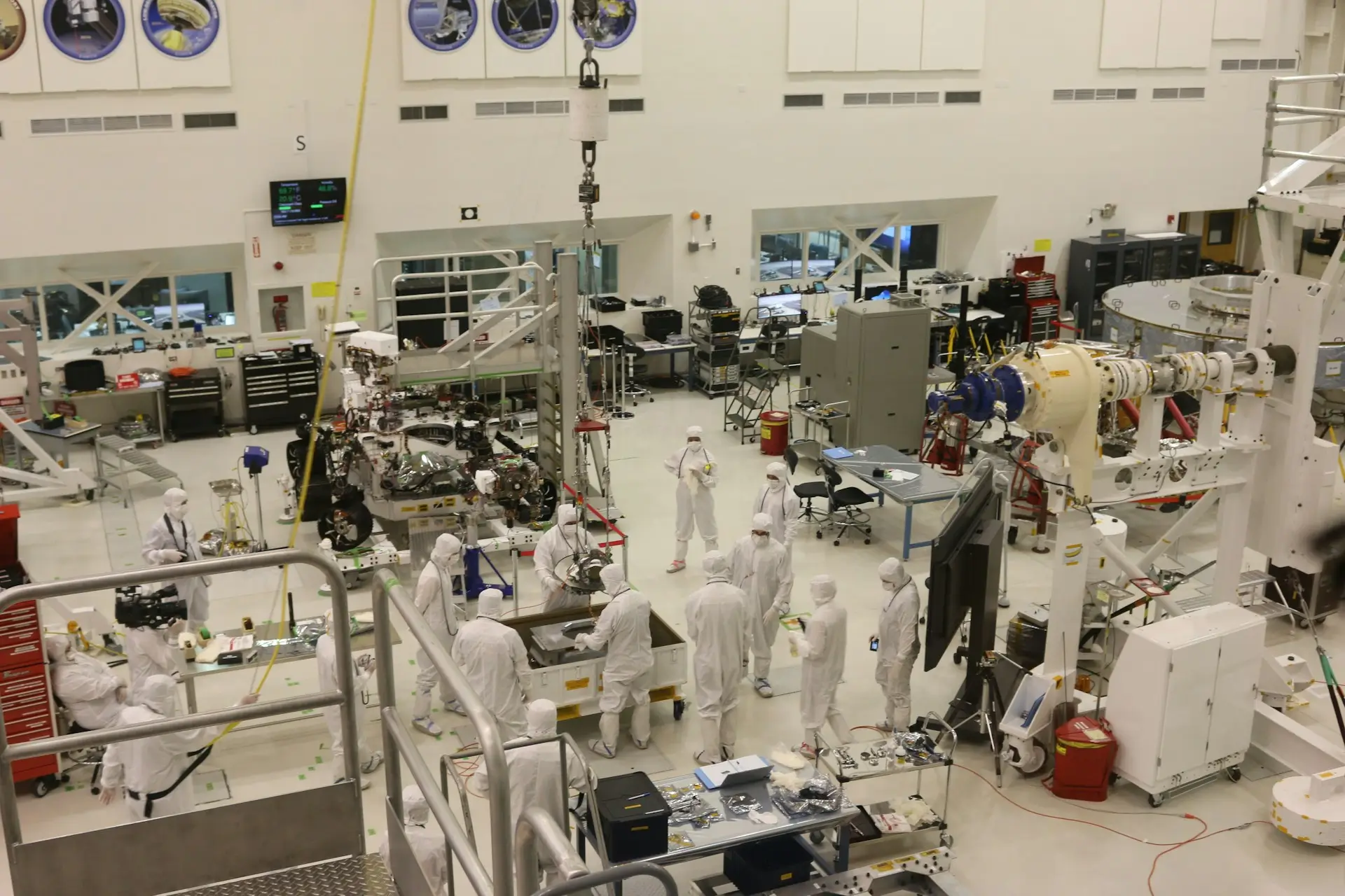 Insights Blog 8 Large cleanroom assembly facility with technicians in protective suits working on complex equipment.