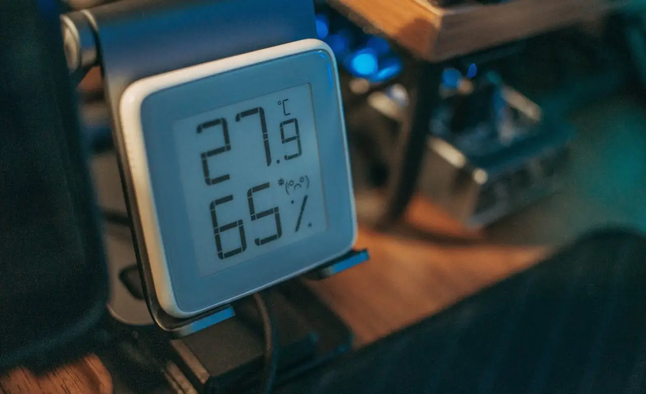 Digital humidity meter showing temperature and relative humidity in an indoor setting.