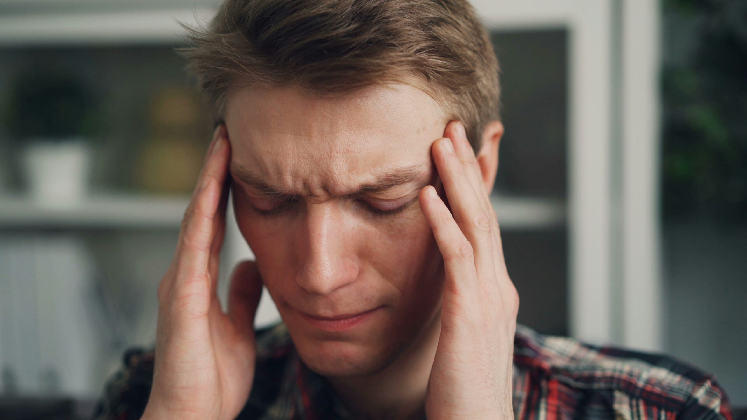 Young man with headache, looking distressed.