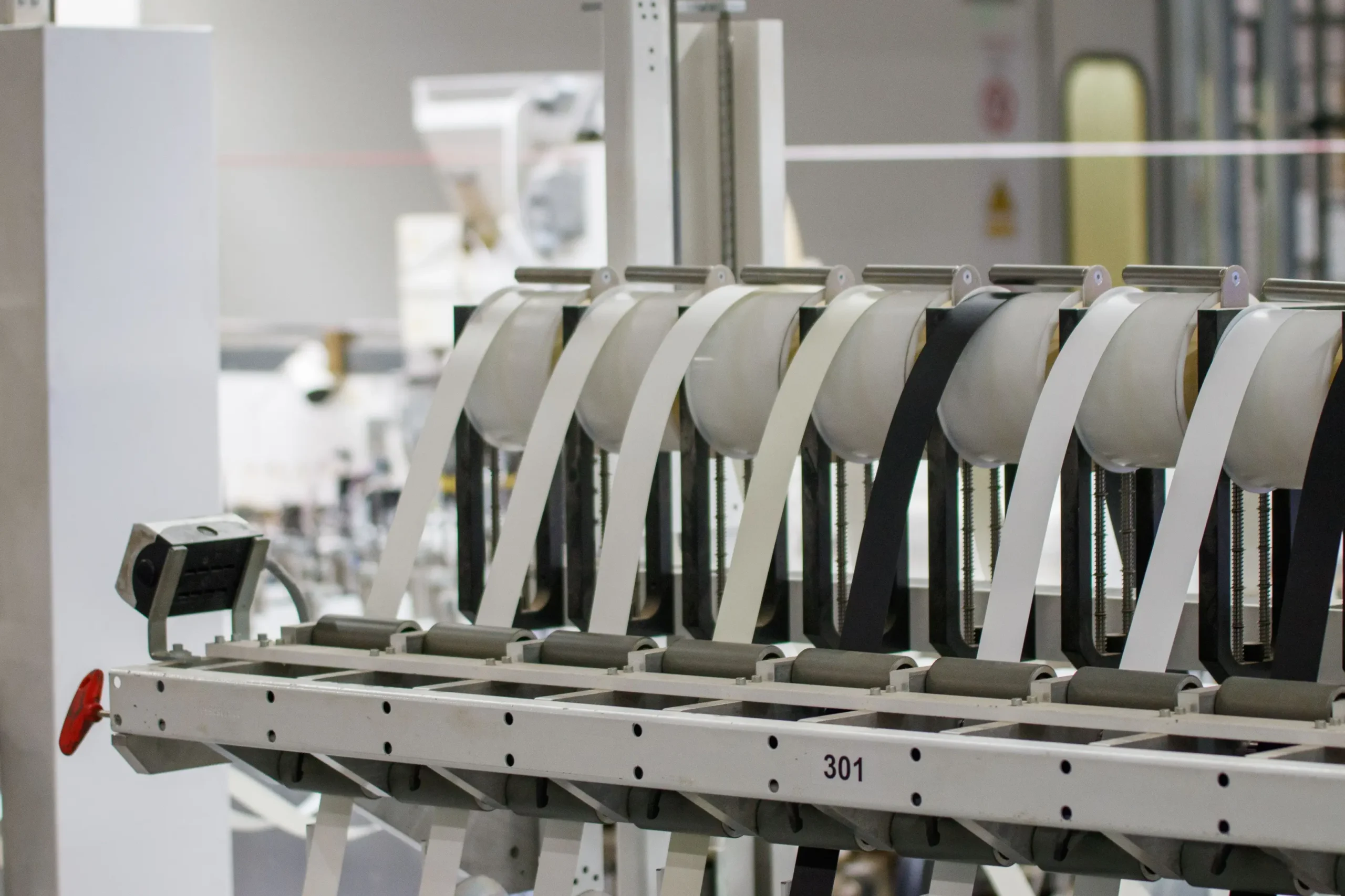 Industrial printing production line with paper reels feeding through rollers and guide mechanisms used for high-speed commercial printing and converting operations.