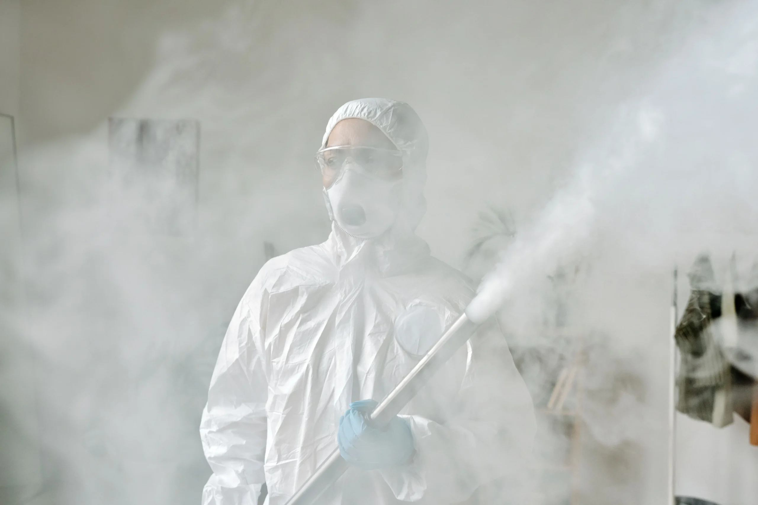 Insights Blog 2 Technician wearing protective coveralls, goggles, and a respirator using fogging equipment inside an electronics manufacturing environment to support ESD-safe humidity control.