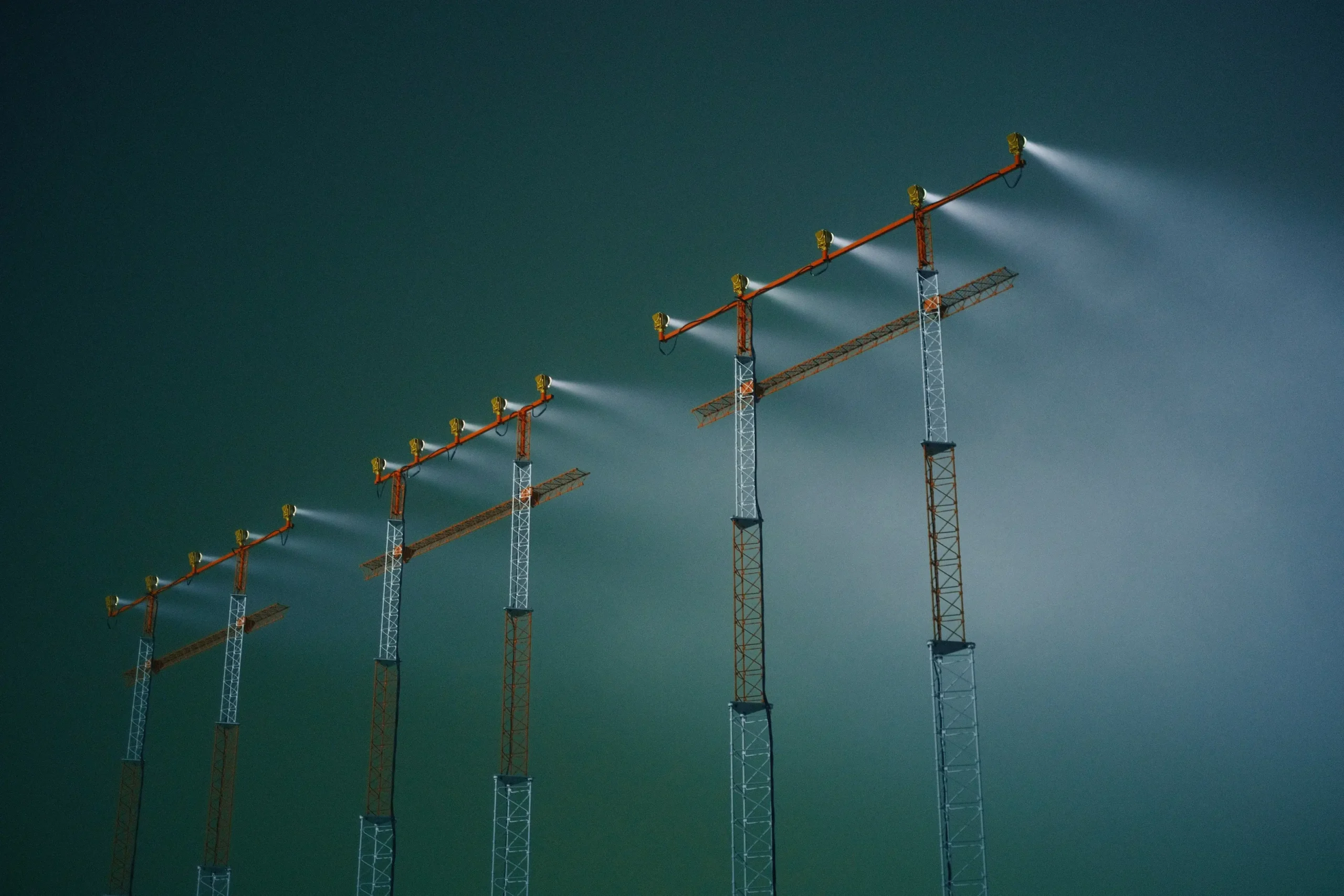 Insights Blog 1 Construction site tower cranes fitted with high-pressure misting nozzles releasing fine water spray for dust suppression and air quality control during industrial and infrastructure projects.