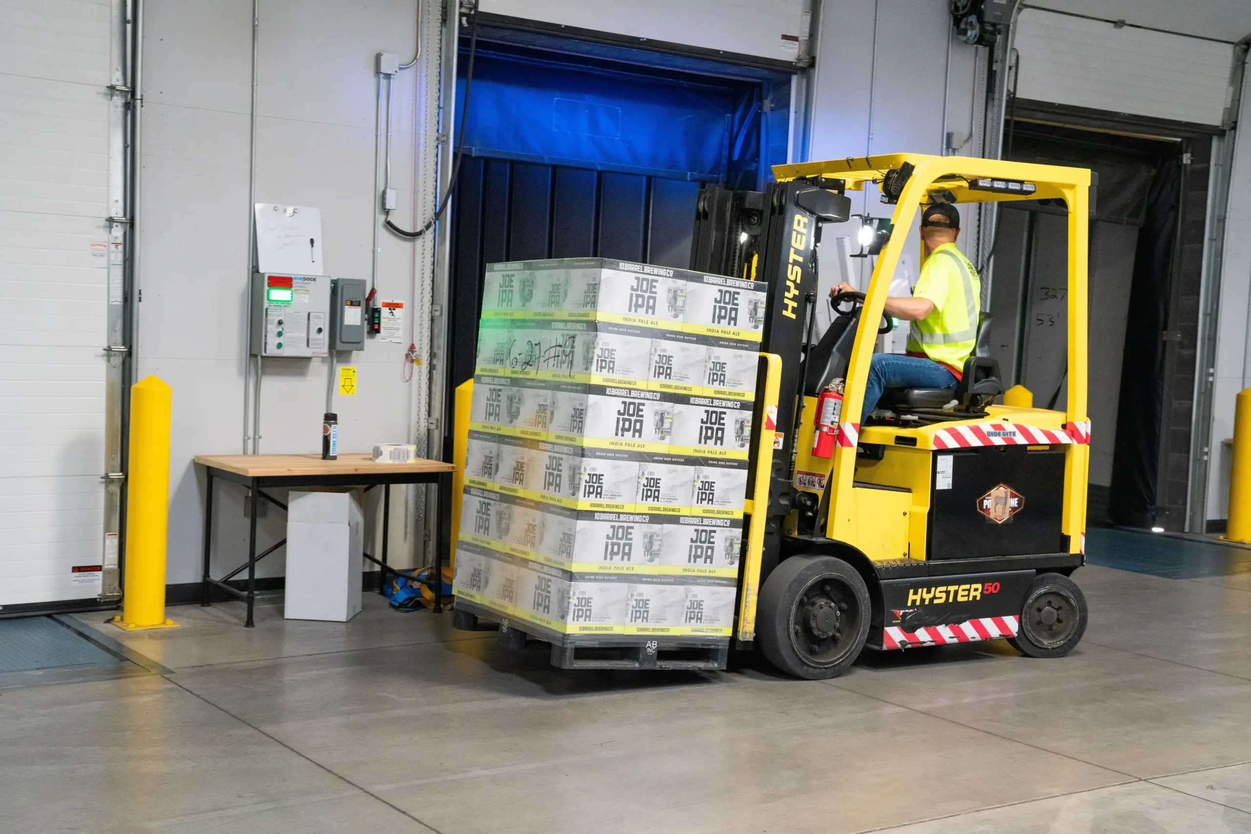 Insights Blog 9 Forklift transporting palletised goods through a warehouse loading dock with integrated HVAC doors, illustrating an industrial distribution environment where in-duct humidification supports facility-wide humidity control.