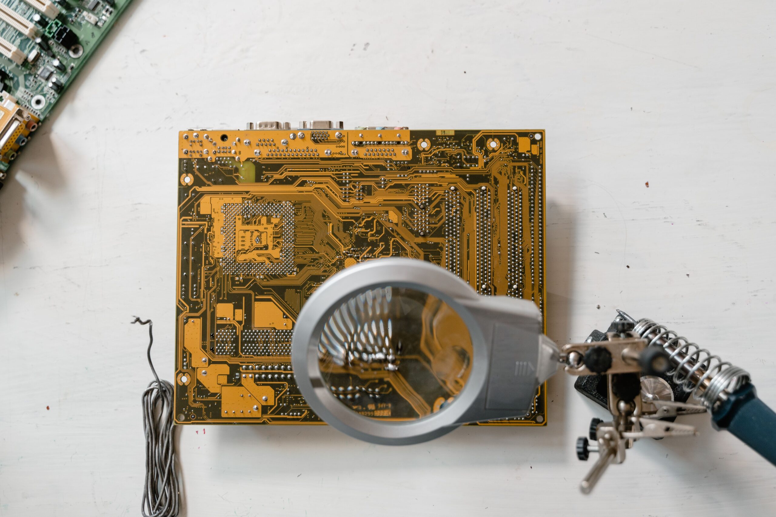 Insights Blog 7 Magnifying lens positioned over a printed circuit board during close inspection and ESD failure analysis.