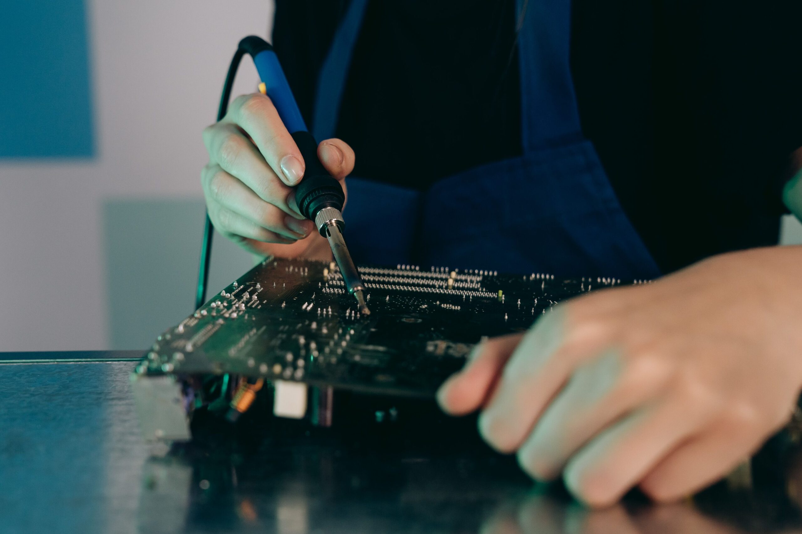Insights Blog 8 Technician using a soldering iron to repair or assemble an electronic circuit board at an ESD-safe workstation.
