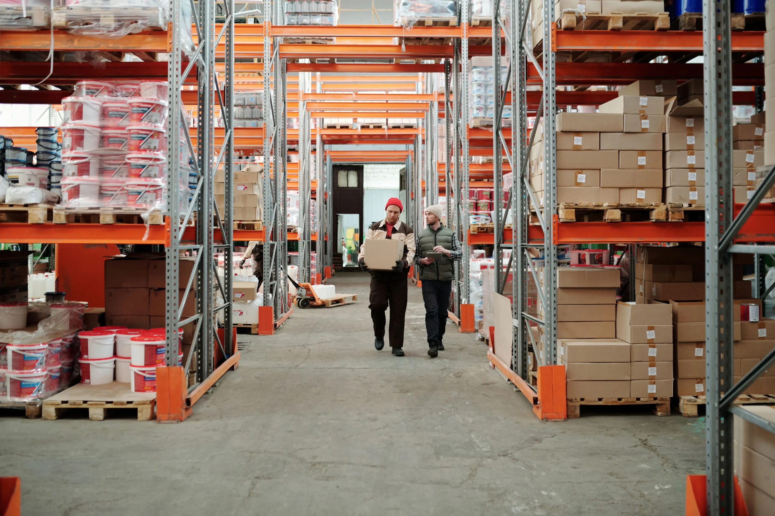 Insights Blog 4 Industrial warehouse workers moving inventory through a large distribution facility with pallet racking, illustrating an occupied industrial environment where indoor air quality and humidity control support worker comfort and operational efficiency.