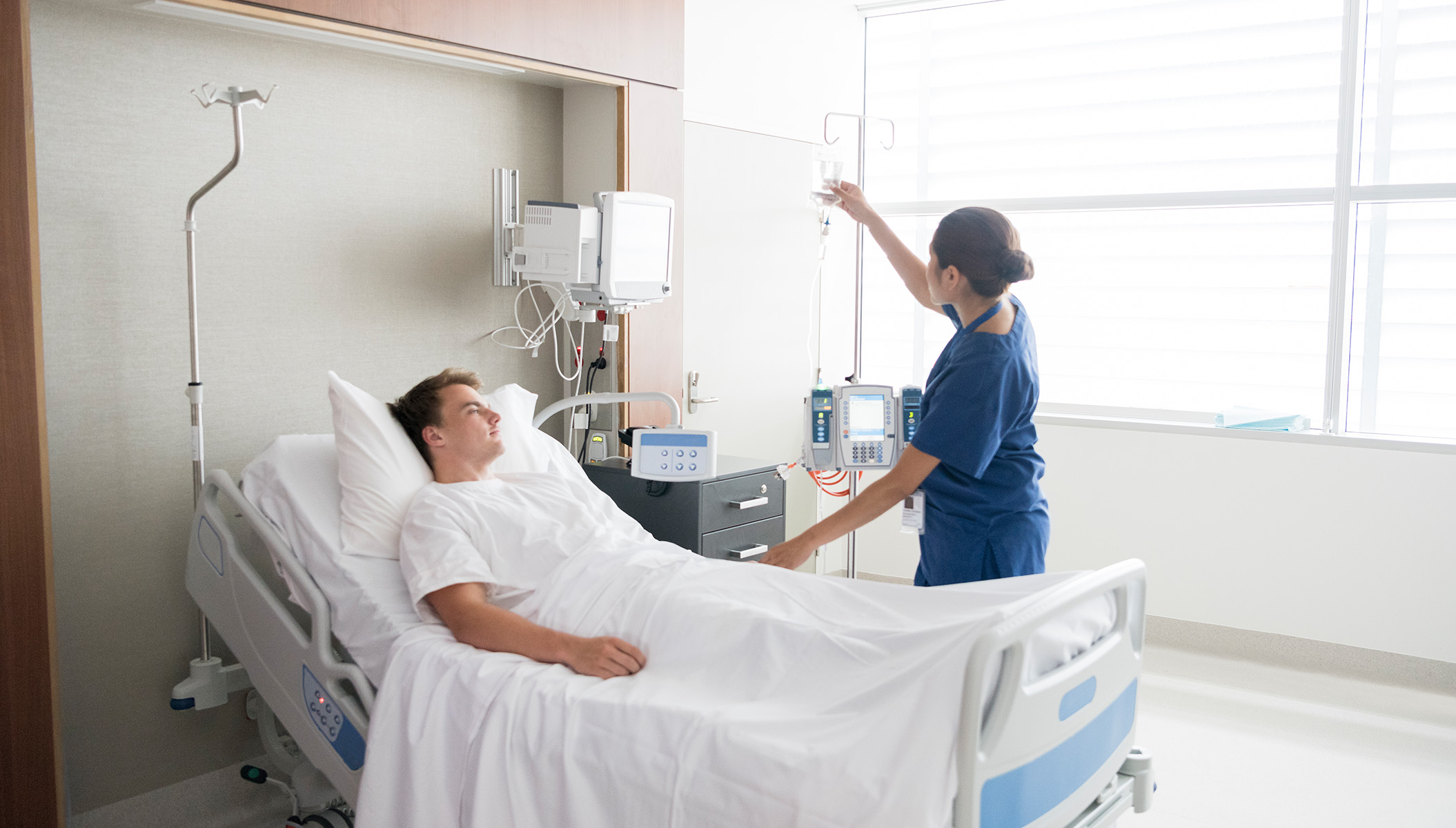 Insights Blog 1 Nurse caring for a patient in a hospital room, the setting where humidity control helps limit airborne virus transmission.
