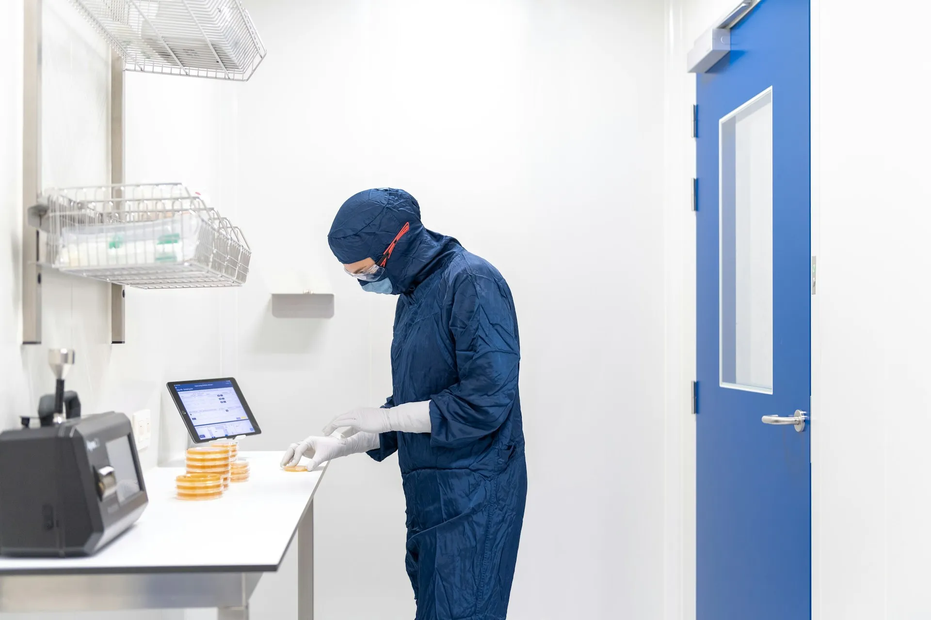 Gowned technician adjusting a wall-mounted touchscreen panel controlling non-wetting humidification in a clean production room