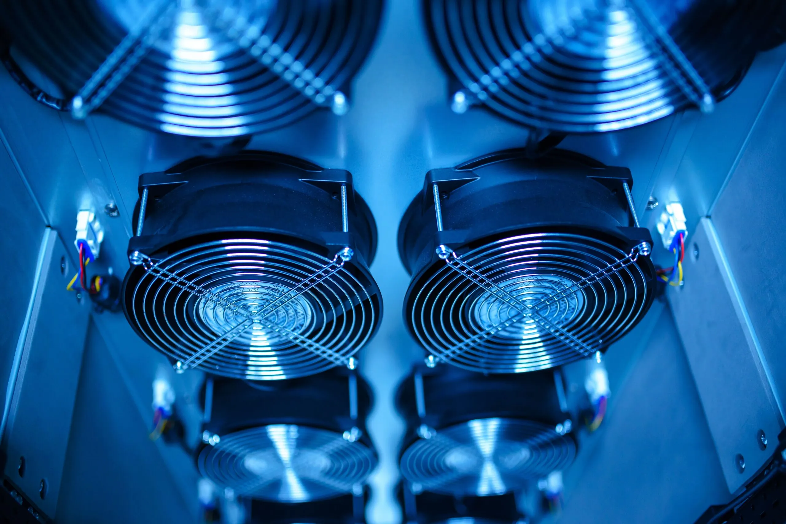 Close-up of industrial cooling fans inside a data center CRAC unit, the traditional air cooling technology reaching its limits at high rack densities.