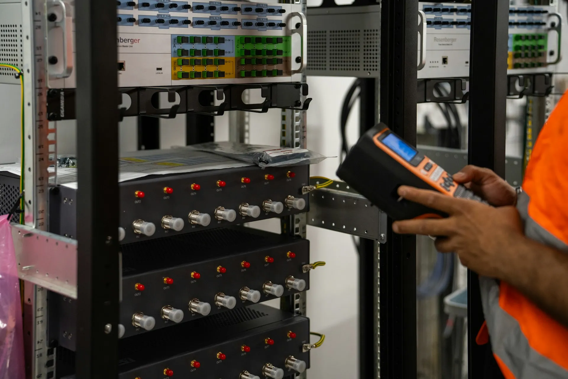 Technician uses a handheld meter to check power distribution units in a server room rack